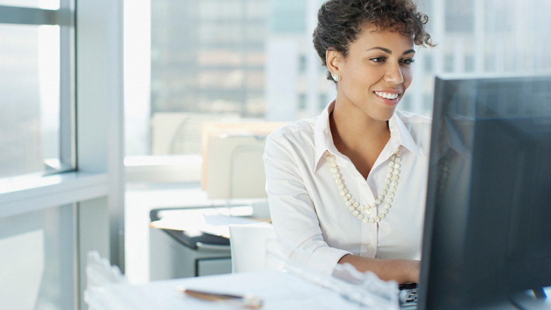 woman sitting at a desk looking at a screen doing healthcare revenue cycle management work