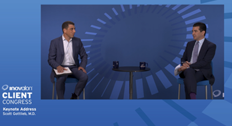 Two men in suits sit on stools facing each other on a blue stage with a circular graphic pattern during the Inovalon Client Congress 2020. A small table with two mugs is between them, as the screen reads Keynote Address Scott Gottlieb, M.D.