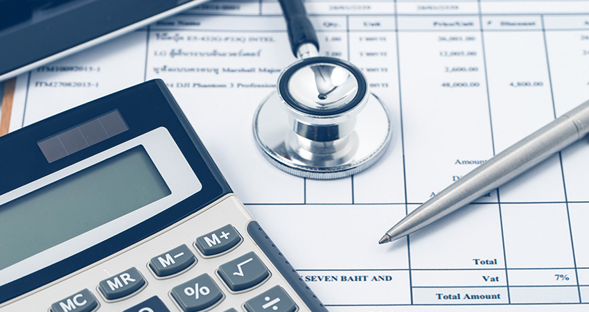 A calculator, stethoscope, and pen rest on a medical invoice, symbolizing healthcare costs and medical billing during the COVID public health emergency.