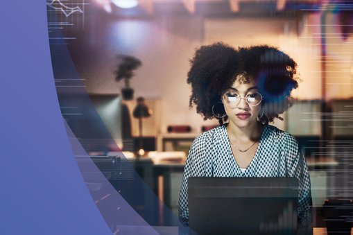 A woman with curly hair and glasses sits at a desk, working on a laptop in a modern, softly lit office. Digital graphics overlay the image, reflecting Real World Data analysis, with a purple shape on the left for a high-tech feel.