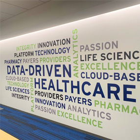 A wall mural with words related to healthcare, such as DATA-DRIVEN, HEALTHCARE, INNOVATION, TECHNOLOGY, ANALYTICS, PHARMACY, and EXCELLENCE in various colors and sizes to inspire efforts to improve healthcare outcomes.