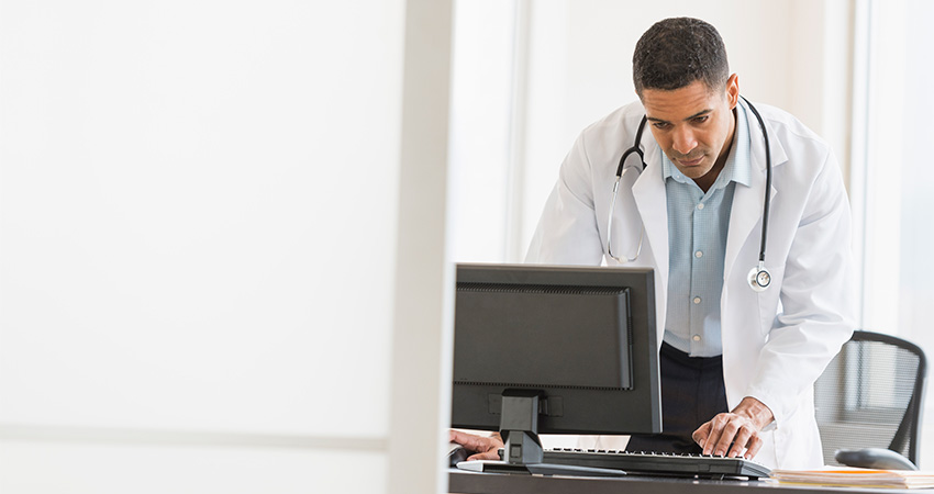 Doctor looks at a desktop computer