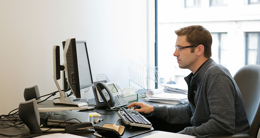 A man sitting at a desk using his computer.