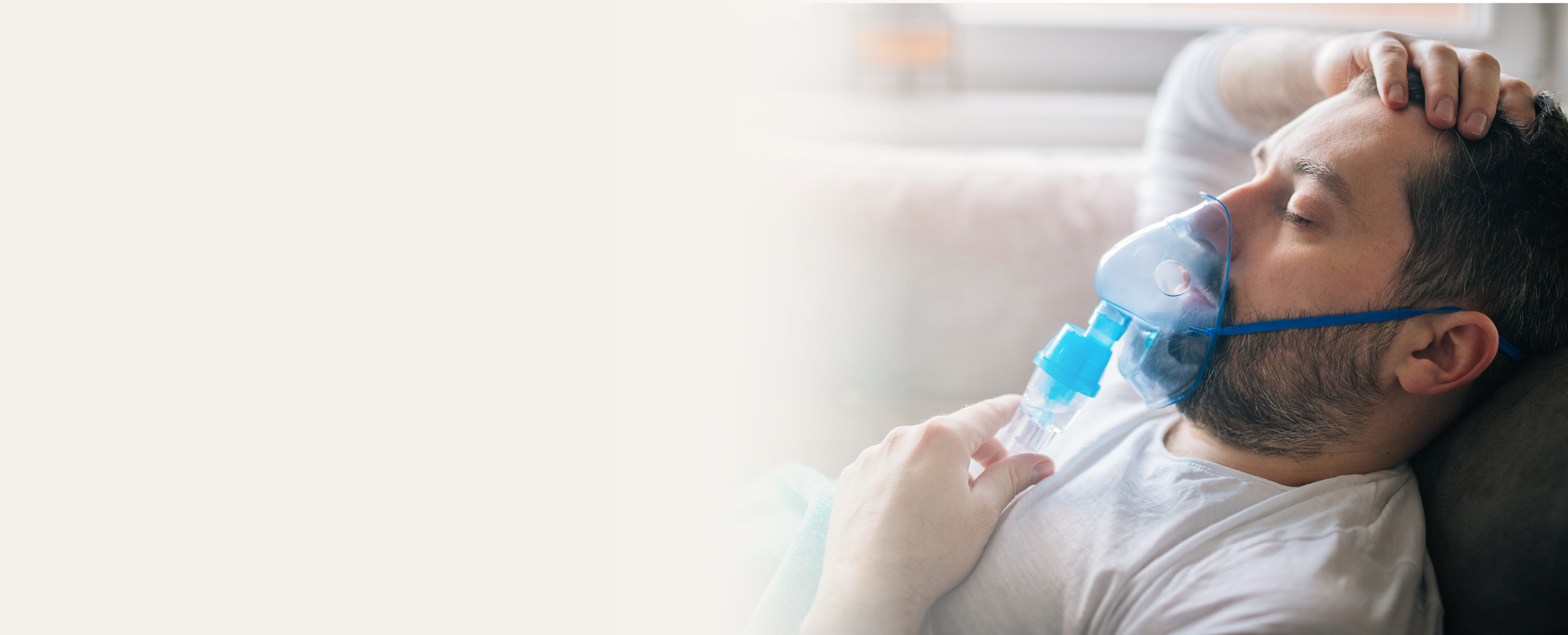 A man lying on a couch with his eyes closed, wearing an oxygen mask and holding a nebulizer, appearing unwell—an image often used in Data Sets for Healthcare to illustrate respiratory conditions.