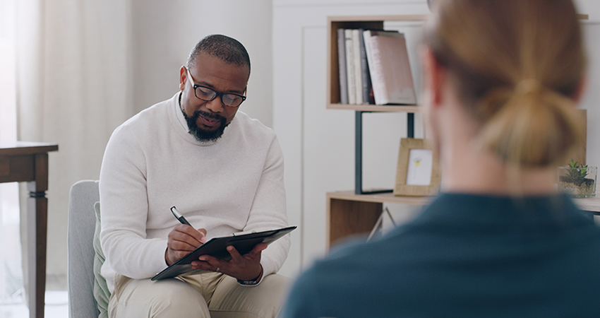 therapist sitting with a patient during a session, looking at notes