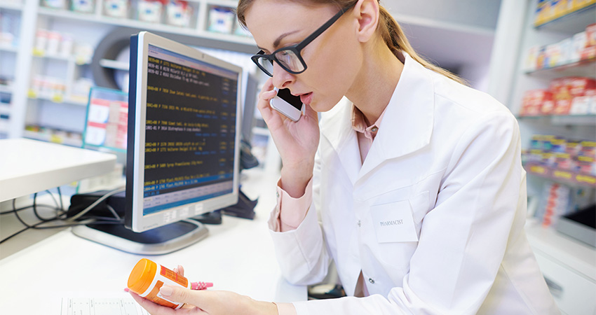 Specialty pharmacist on the phone with a patient reading a medication on bottle