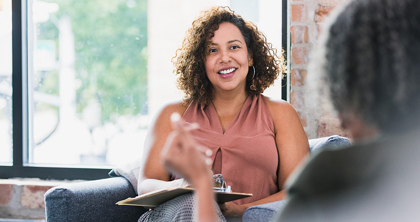 Female mental health therapist sitting down and talking with a patient