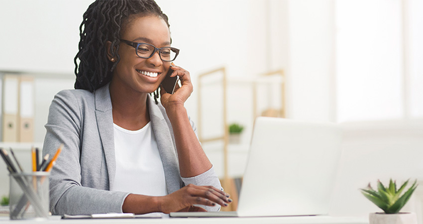 Woman smiling while talking on the phone and looking at laptop computer