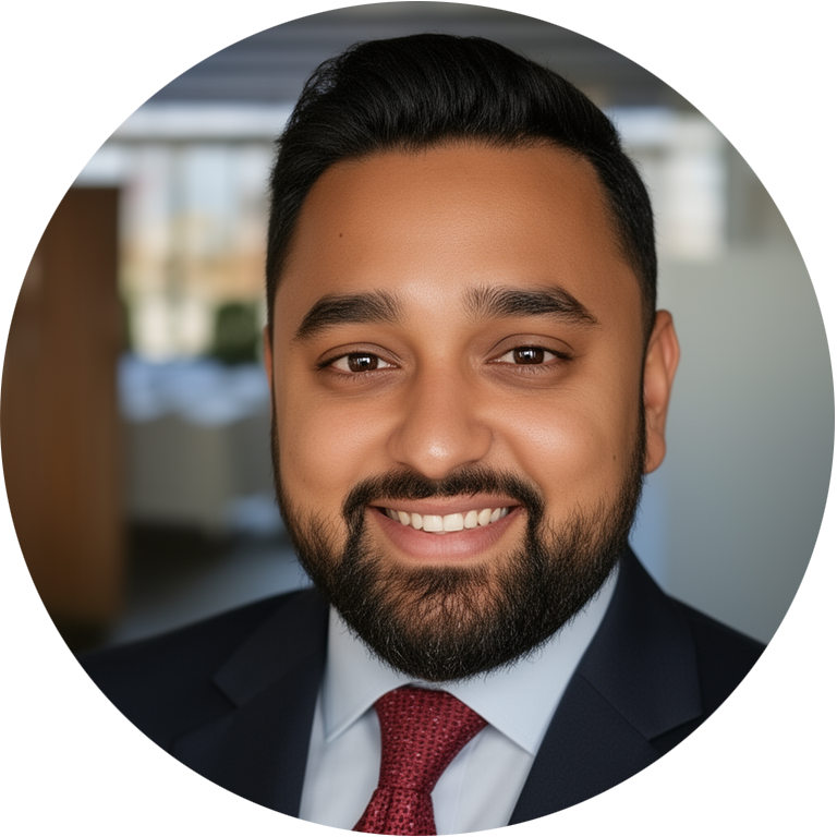 Man with dark hair and beard in a suit smiling for headshot