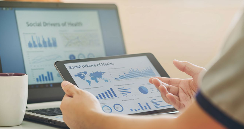 a tablet and laptop on a desk both showing social drivers of health data
