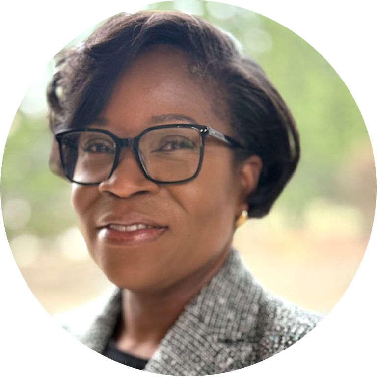 Funke Pickering headshot - woman with short hair and glasses smiling for headshot in a grey blazer