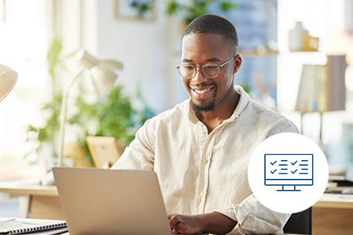 Man working at a desk smiling at his laptop