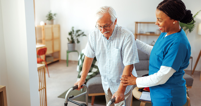 elderly man with walker being supported by medical professional